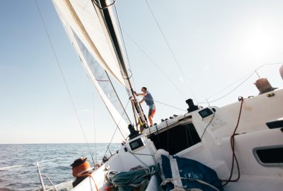 Deck of professional sailboat or racing yacht during competition on sunny and windy summer day, moving fast through waves and water, with spinnaker up, and ropes tied around winch